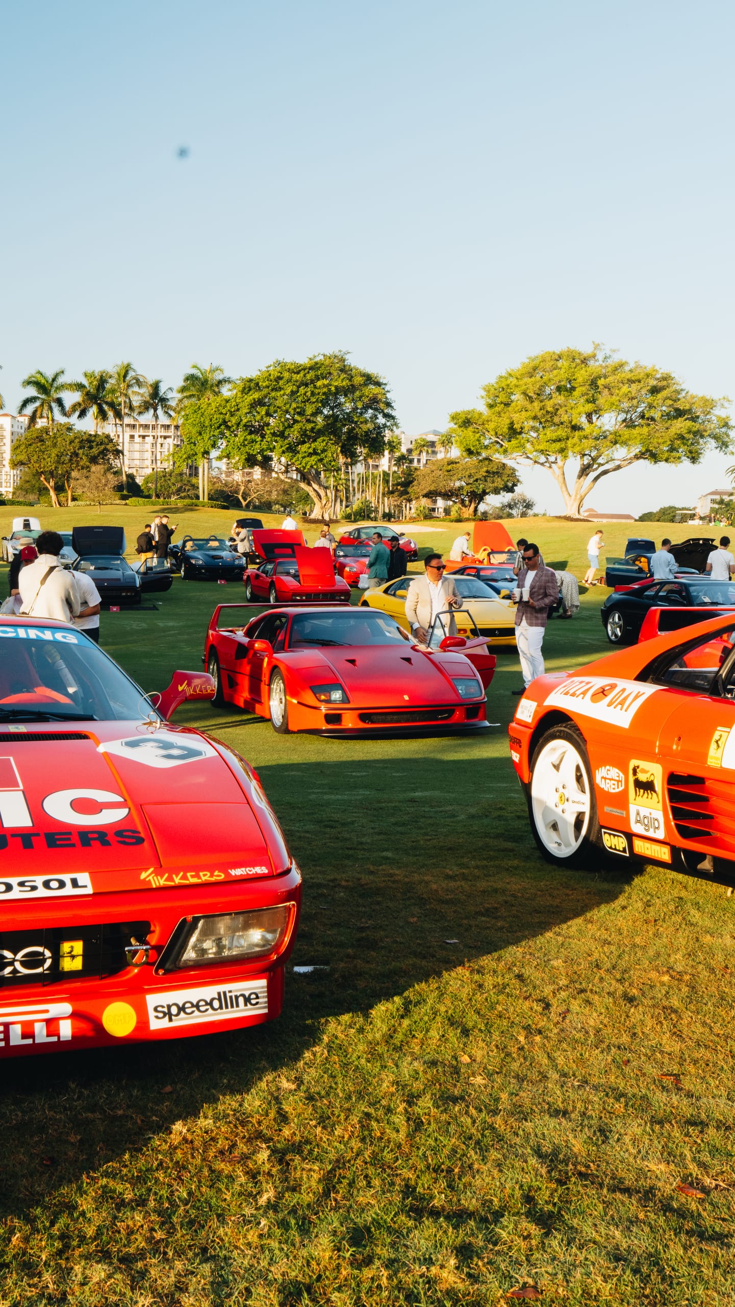 Ferrari F40 and race-liveried Ferraris with attendees walking the concours field