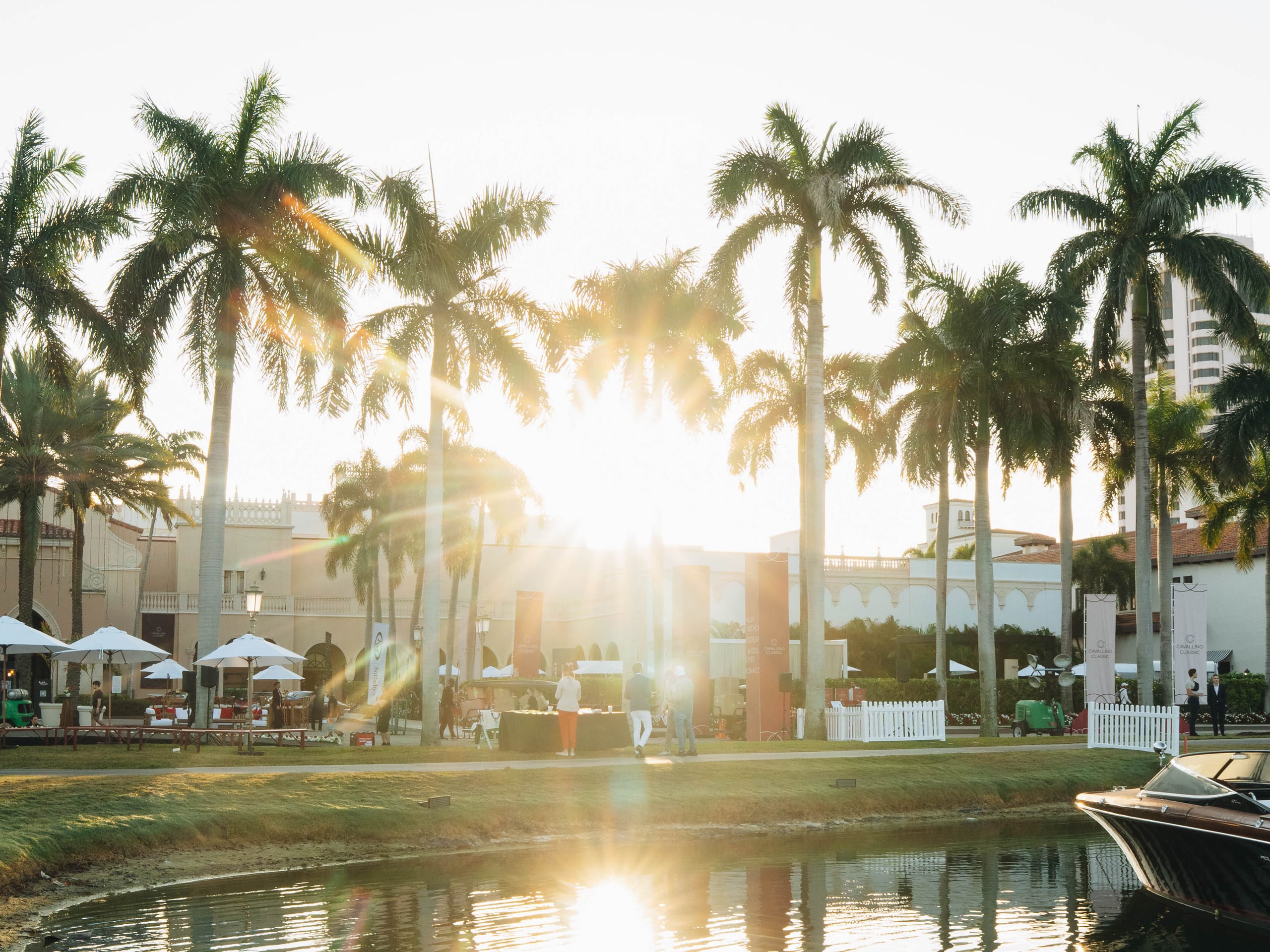 Cavallino Classic venue at sunset with palm trees, hospitality tents, and waterfront