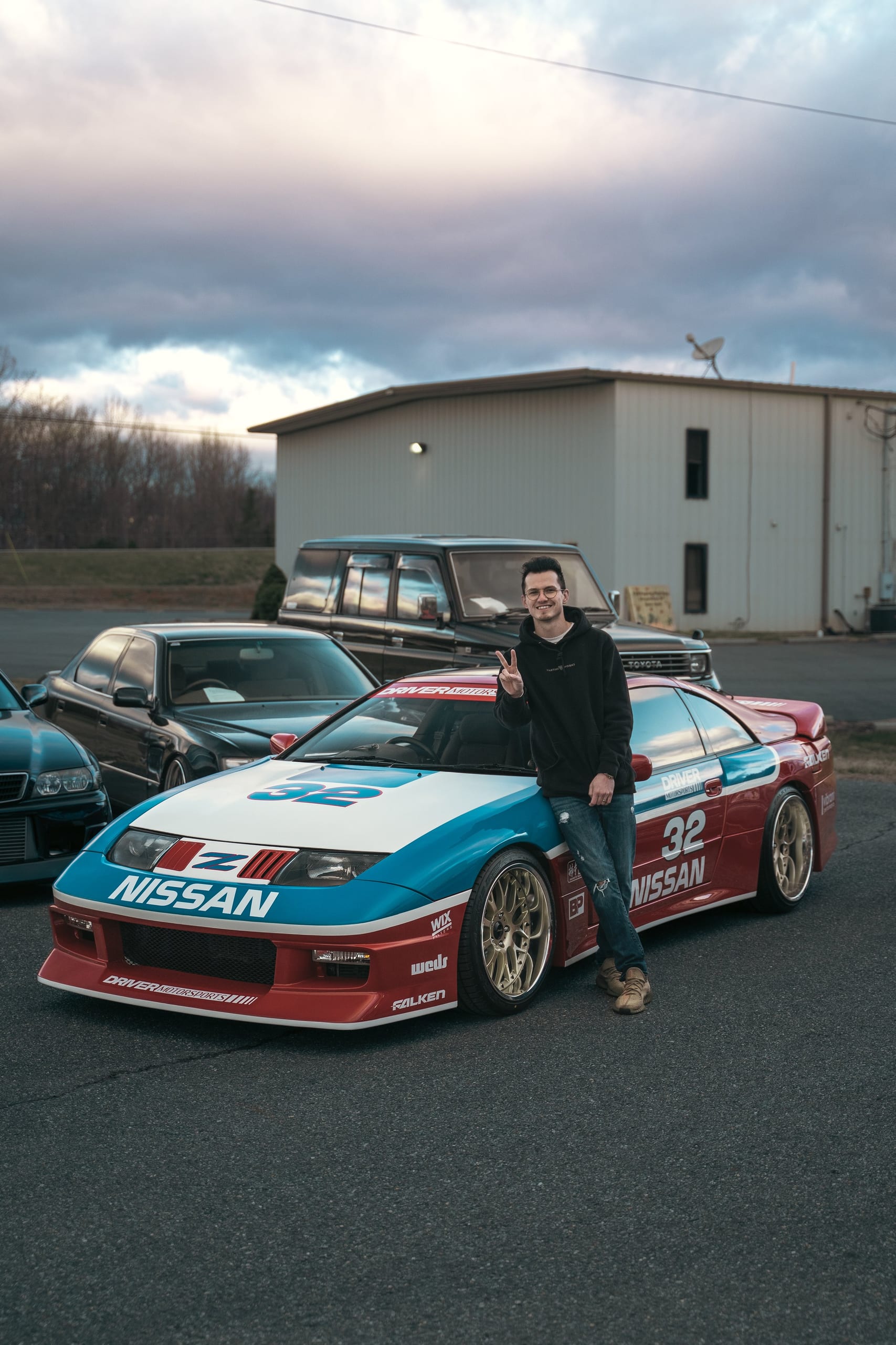 Team member posing with a Nissan Z race car in Driver Motorsports livery