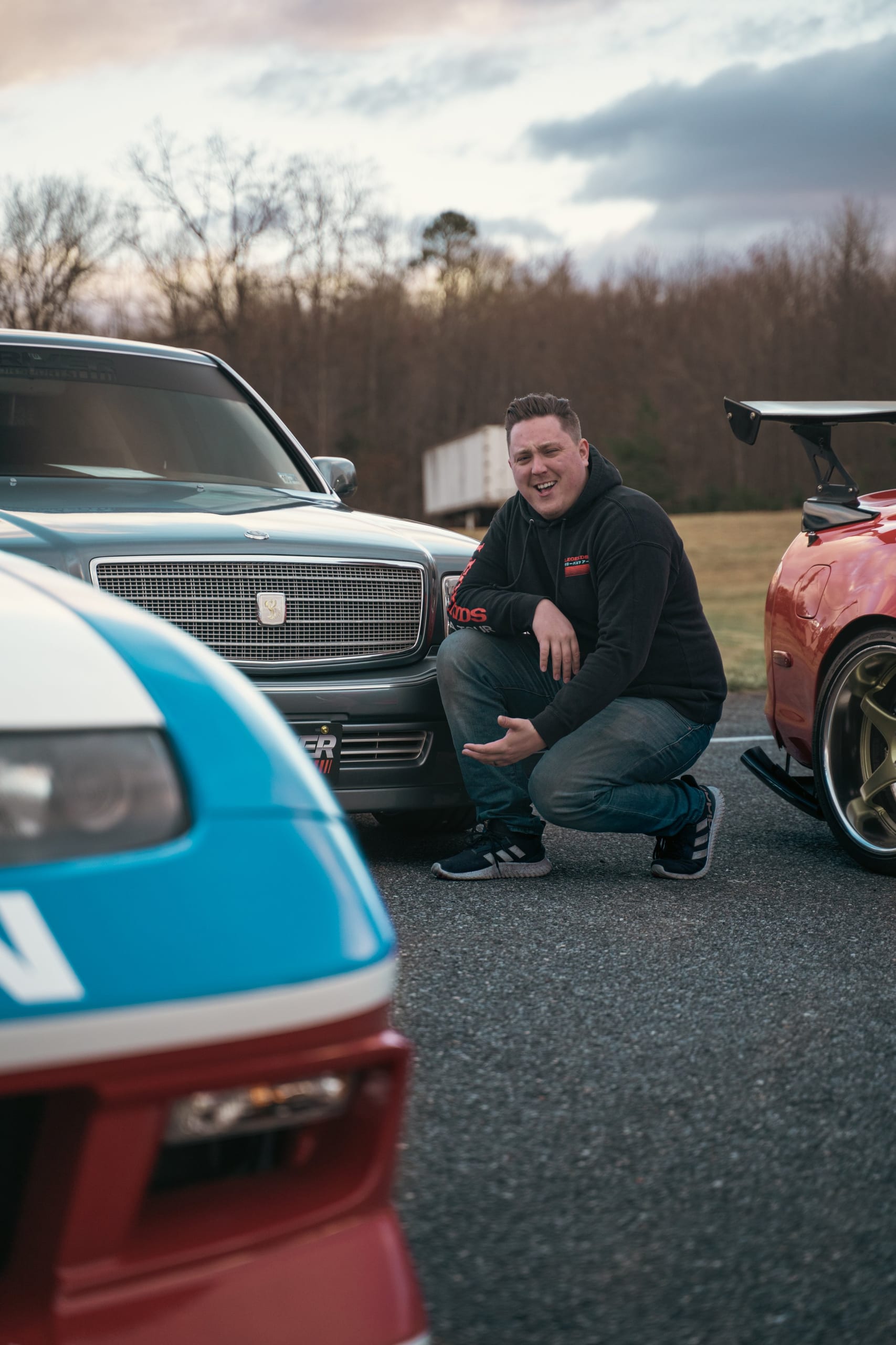 Driver Motorsports team member crouching among JDM builds at golden hour