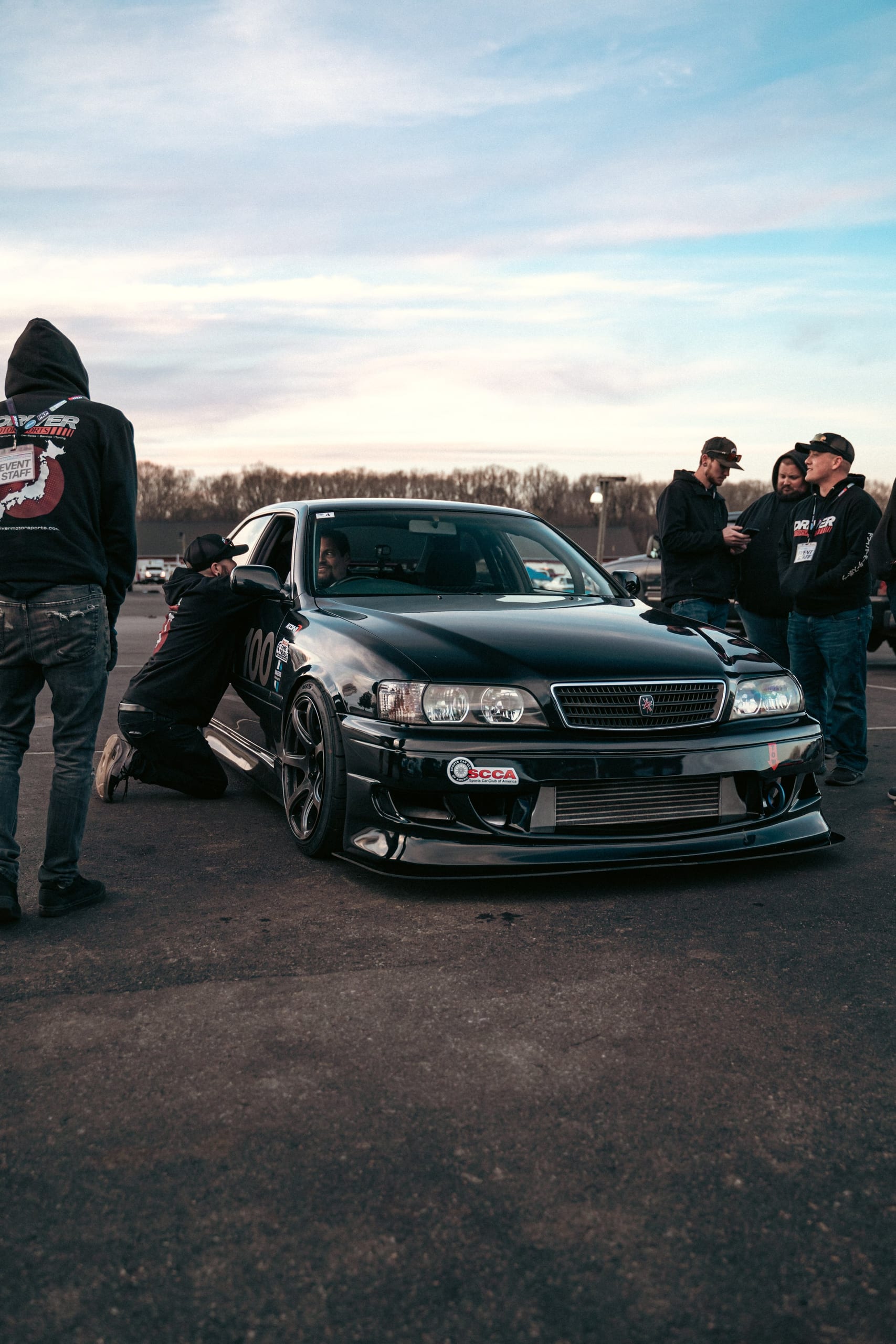 Enthusiasts gathered around a modified Toyota Chaser at a Driver Motorsports community meet