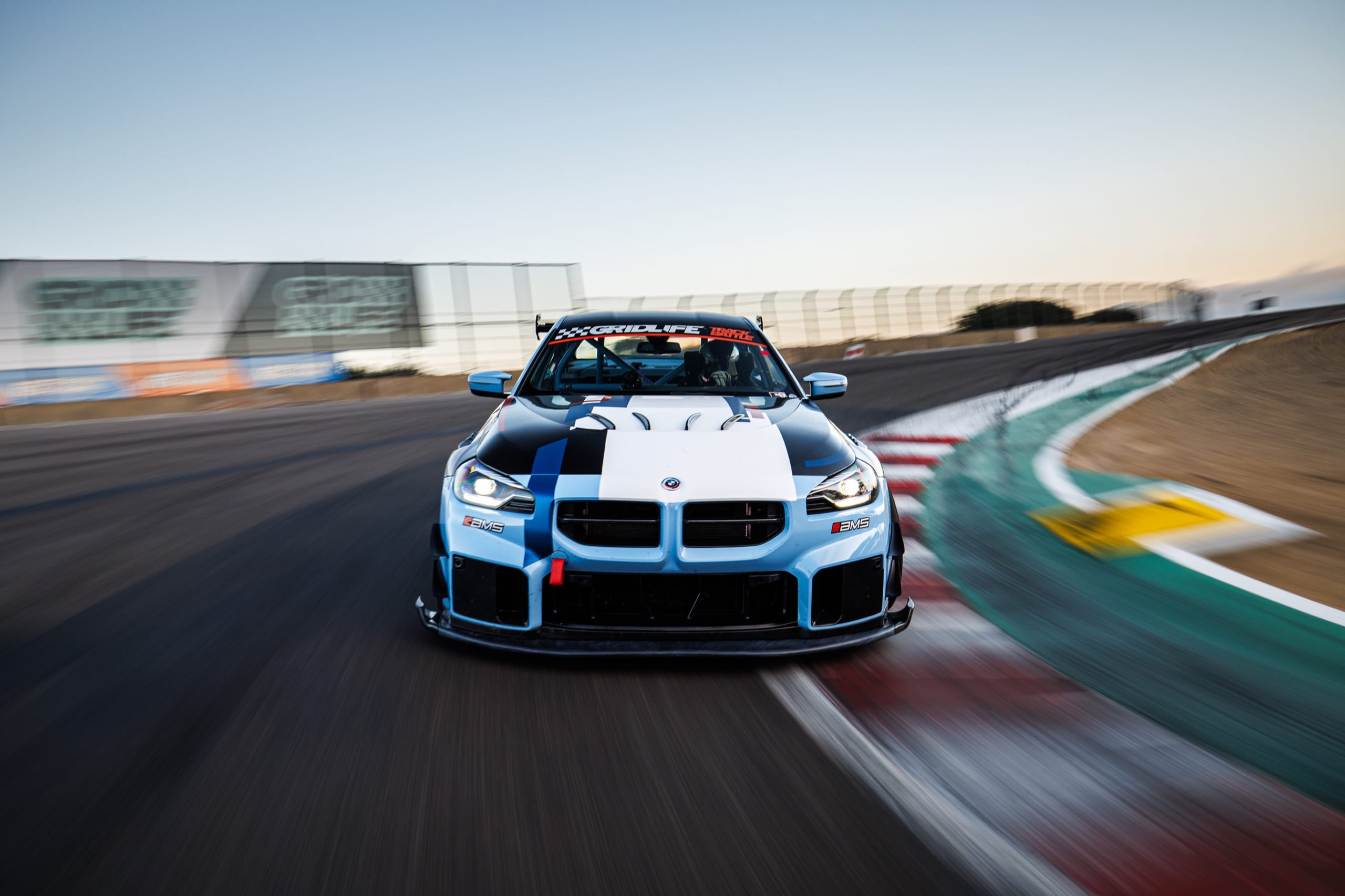 GRIDLIFE-liveried BMW M2 at speed through a corner at golden hour