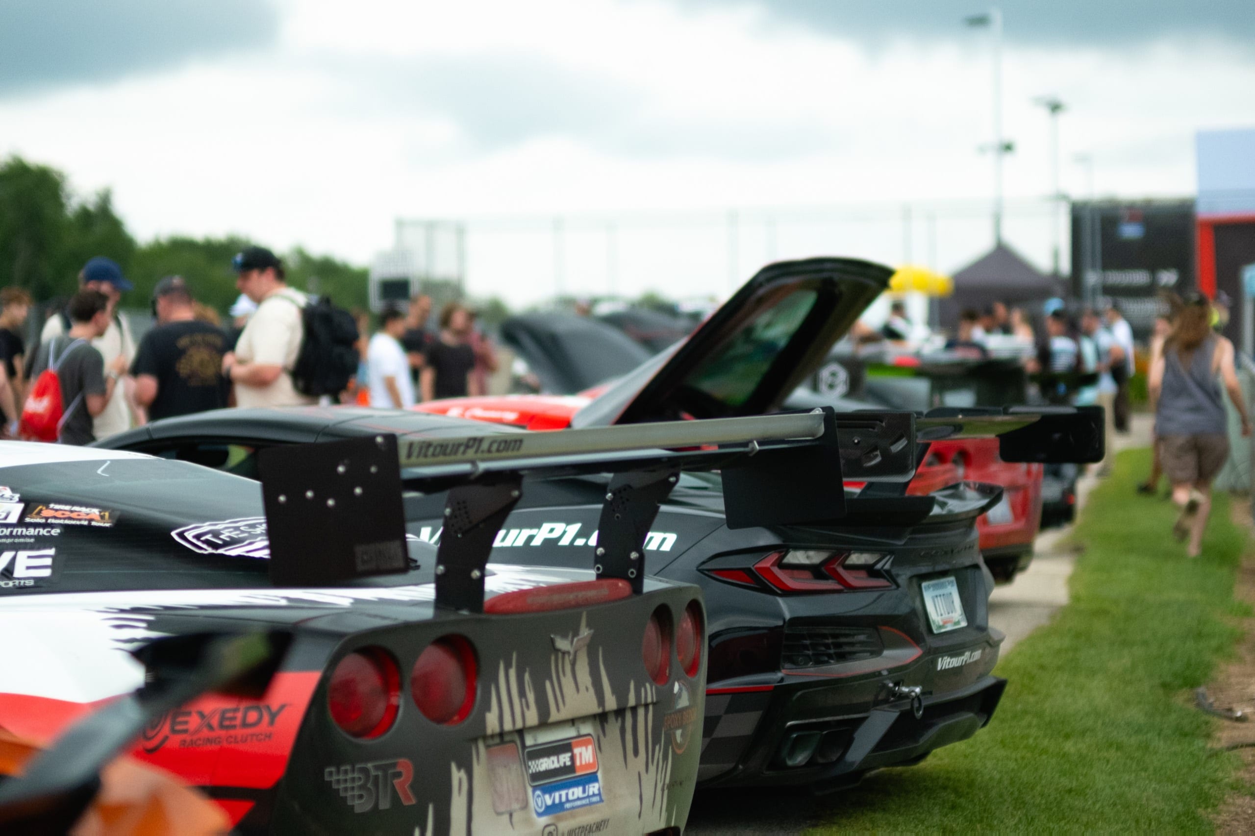 Attendees walking the paddock past winged time-attack car builds at GRIDLIFE
