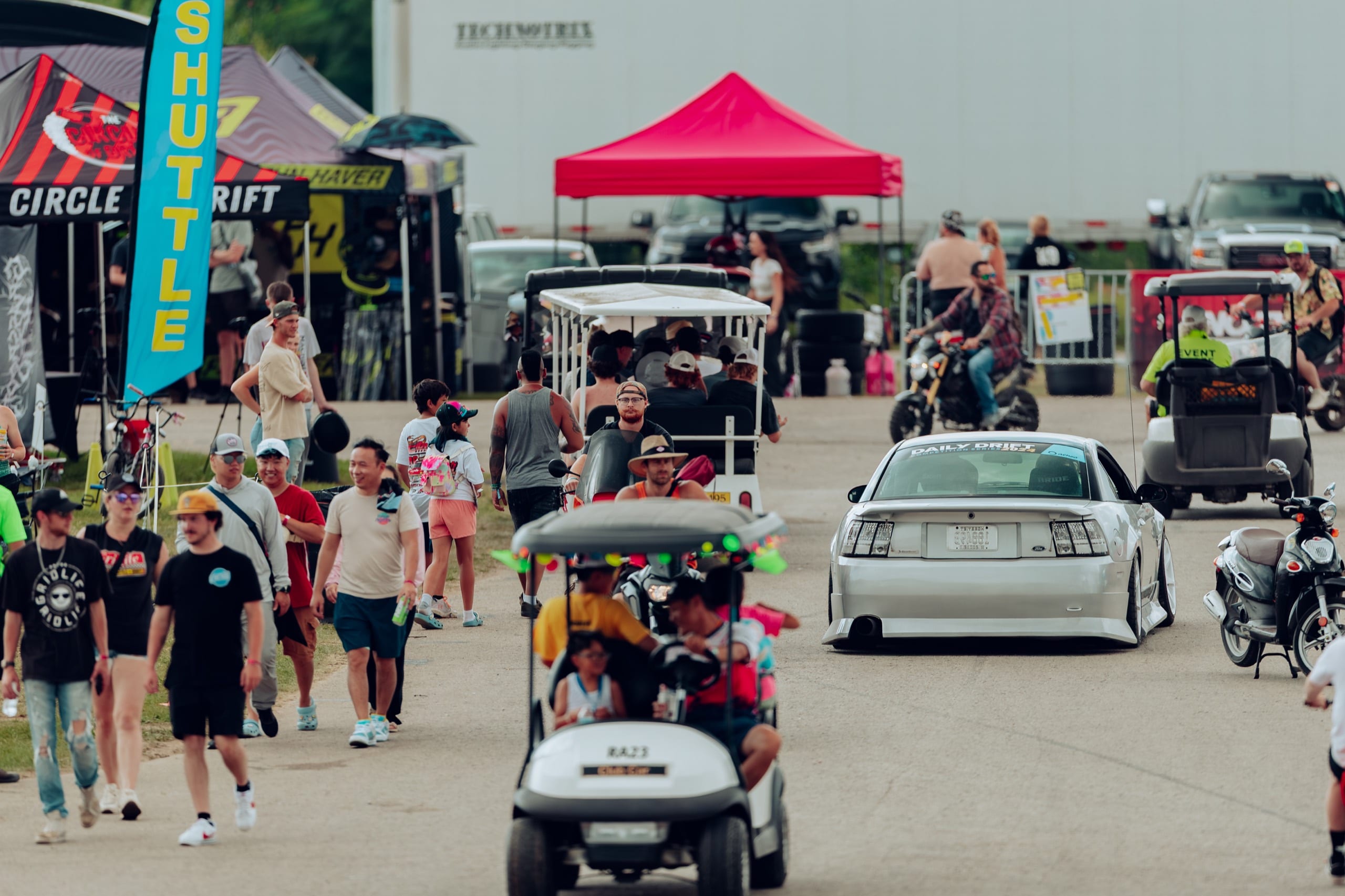 Crowd, vendors, and golf carts filling the midway at GRIDLIFE Summer Apex