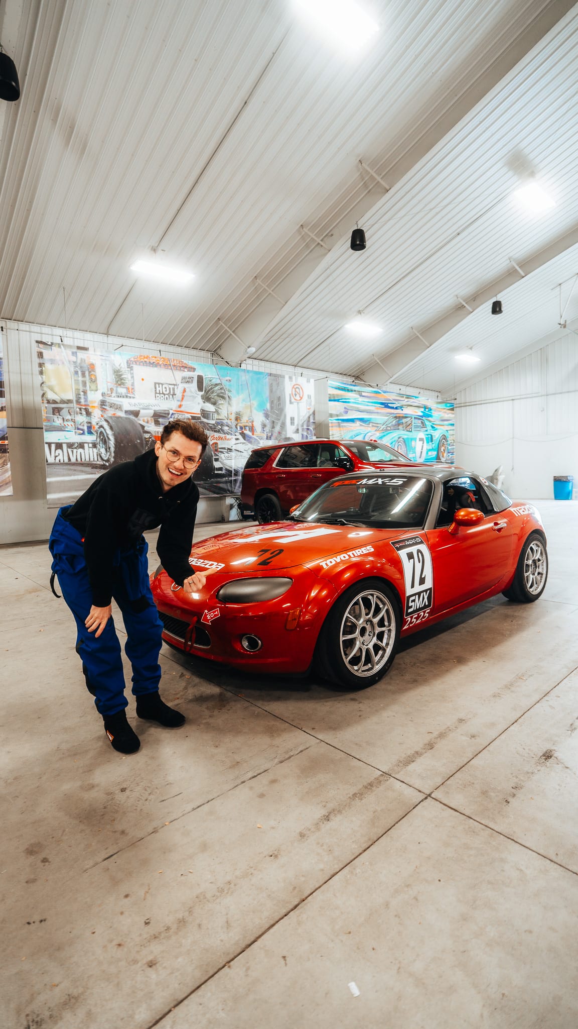AlexMartini standing next to the red Spec MX-5 number 72 in a racing garage