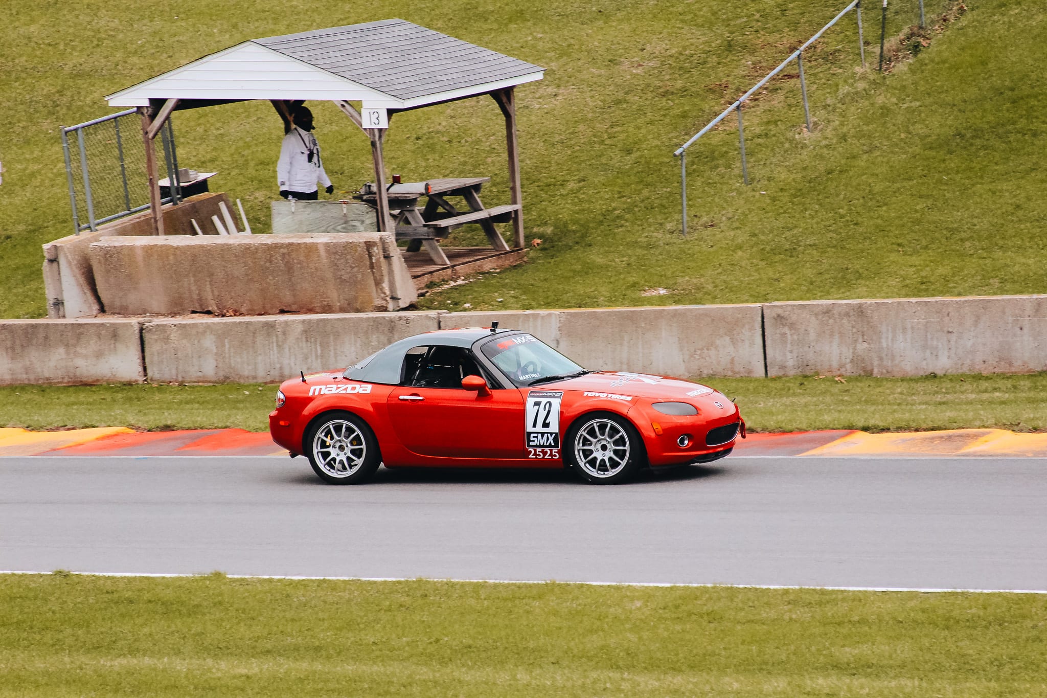 Red Spec MX-5 number 72 racing on track at a Mazda Motorsports event