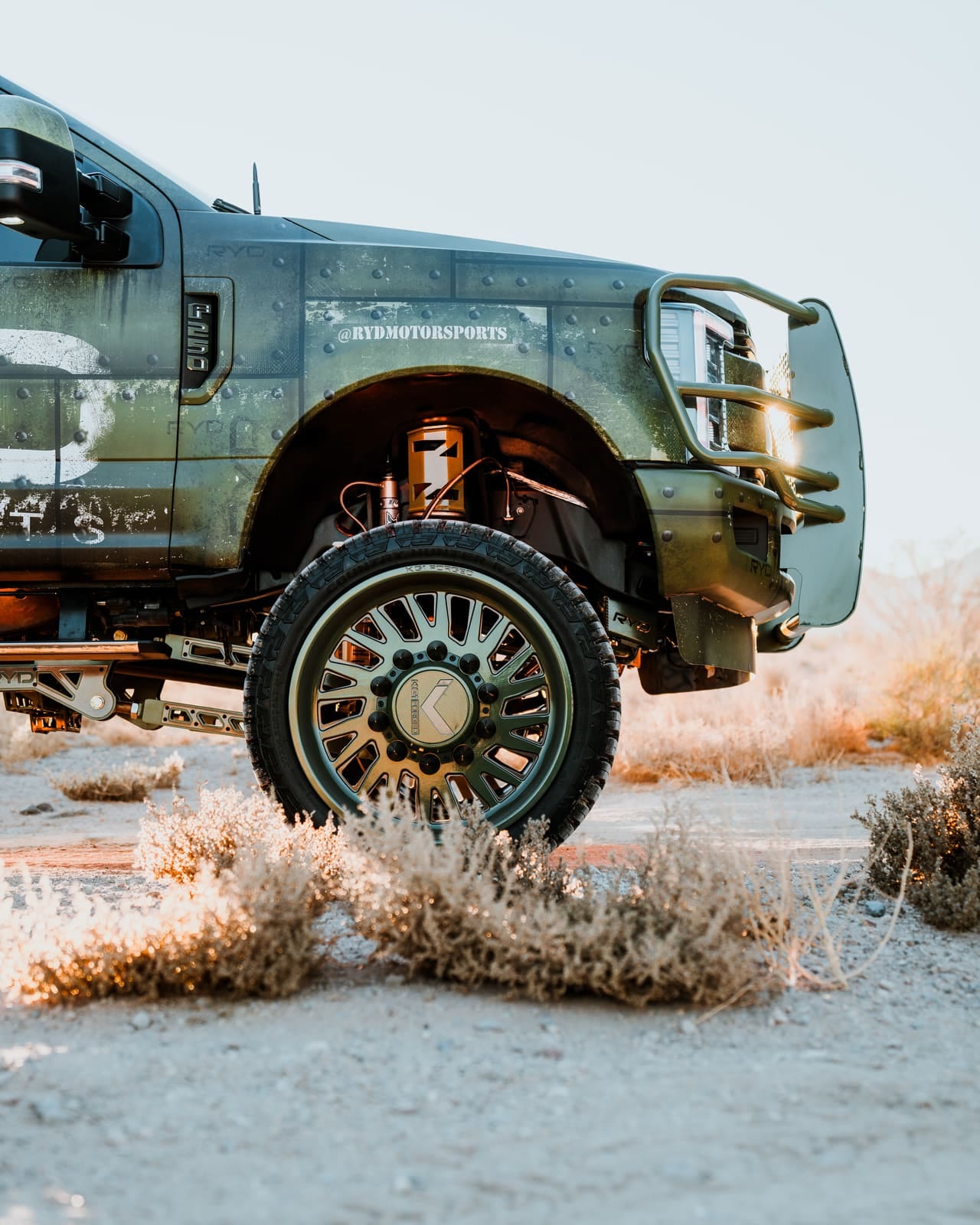 Front wheel and suspension detail of a military-wrapped Ford F-250 on RYD components