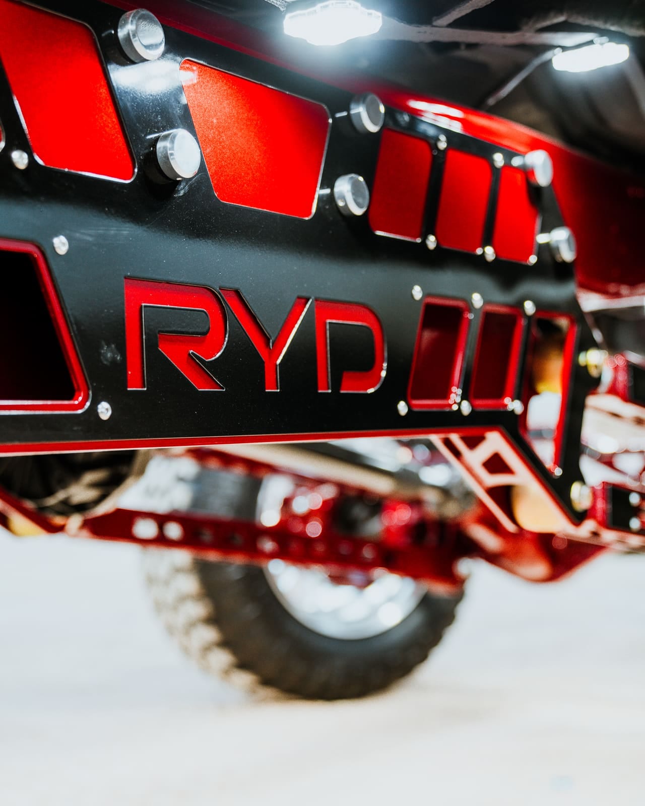 Underside detail of a fabricated RYD skid plate and red suspension components on a lifted truck