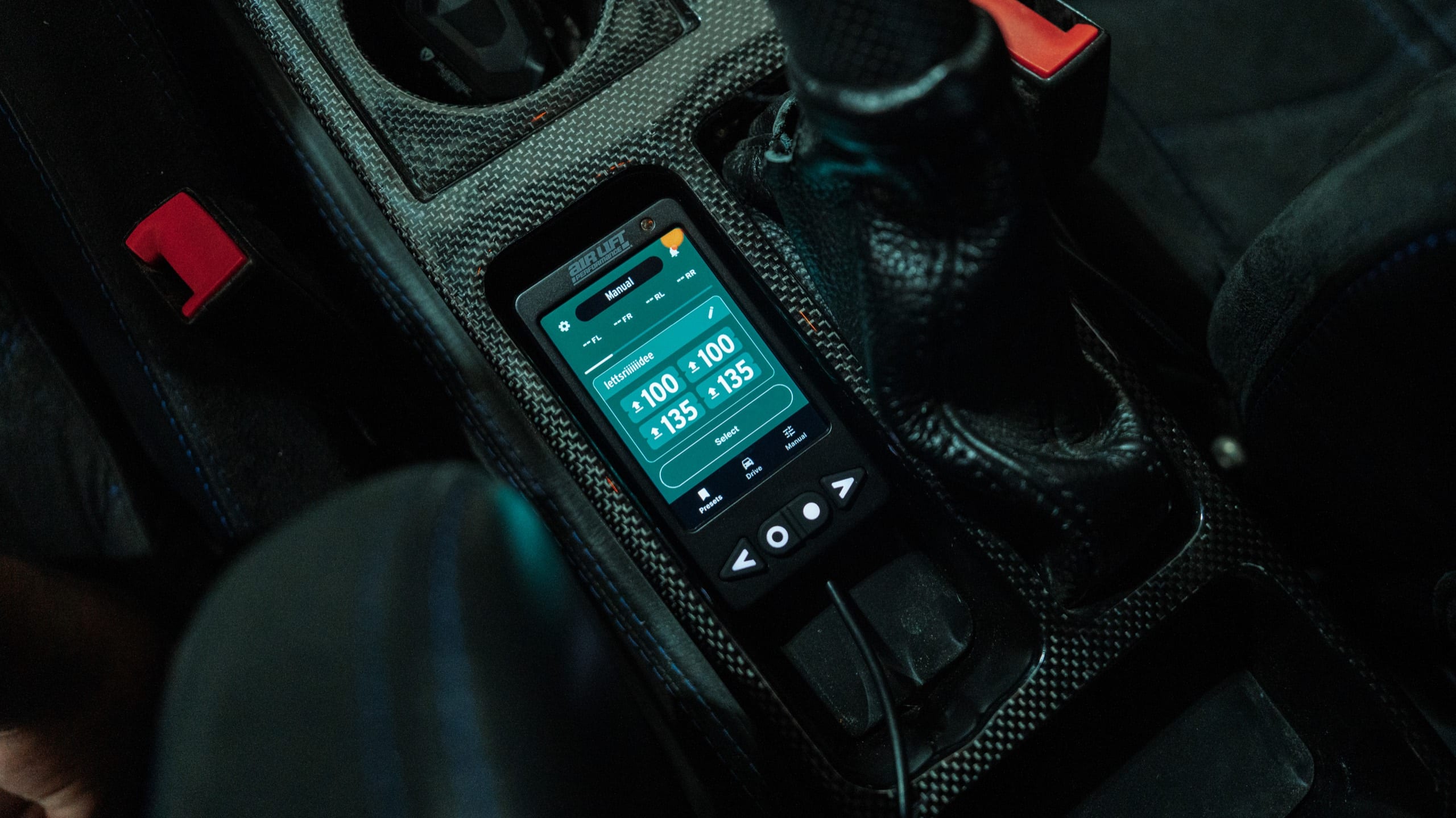 Air Lift Performance controller mounted in a carbon-fiber center console, screen glowing in a Ferrari interior