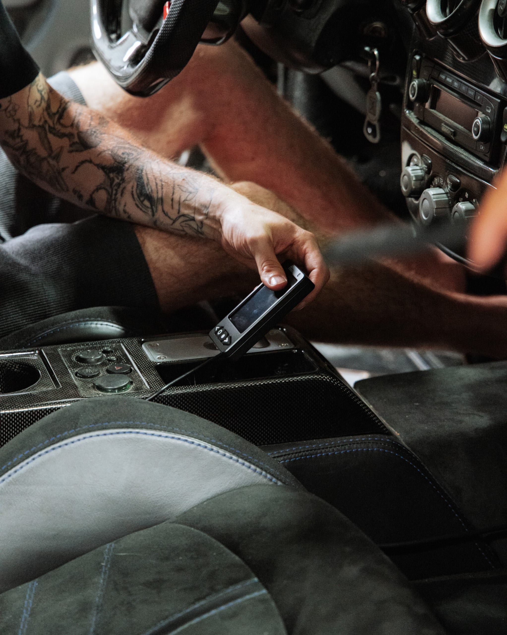 Installer mounting the Air Lift Performance controller in the carbon-fiber console of a Ferrari F430