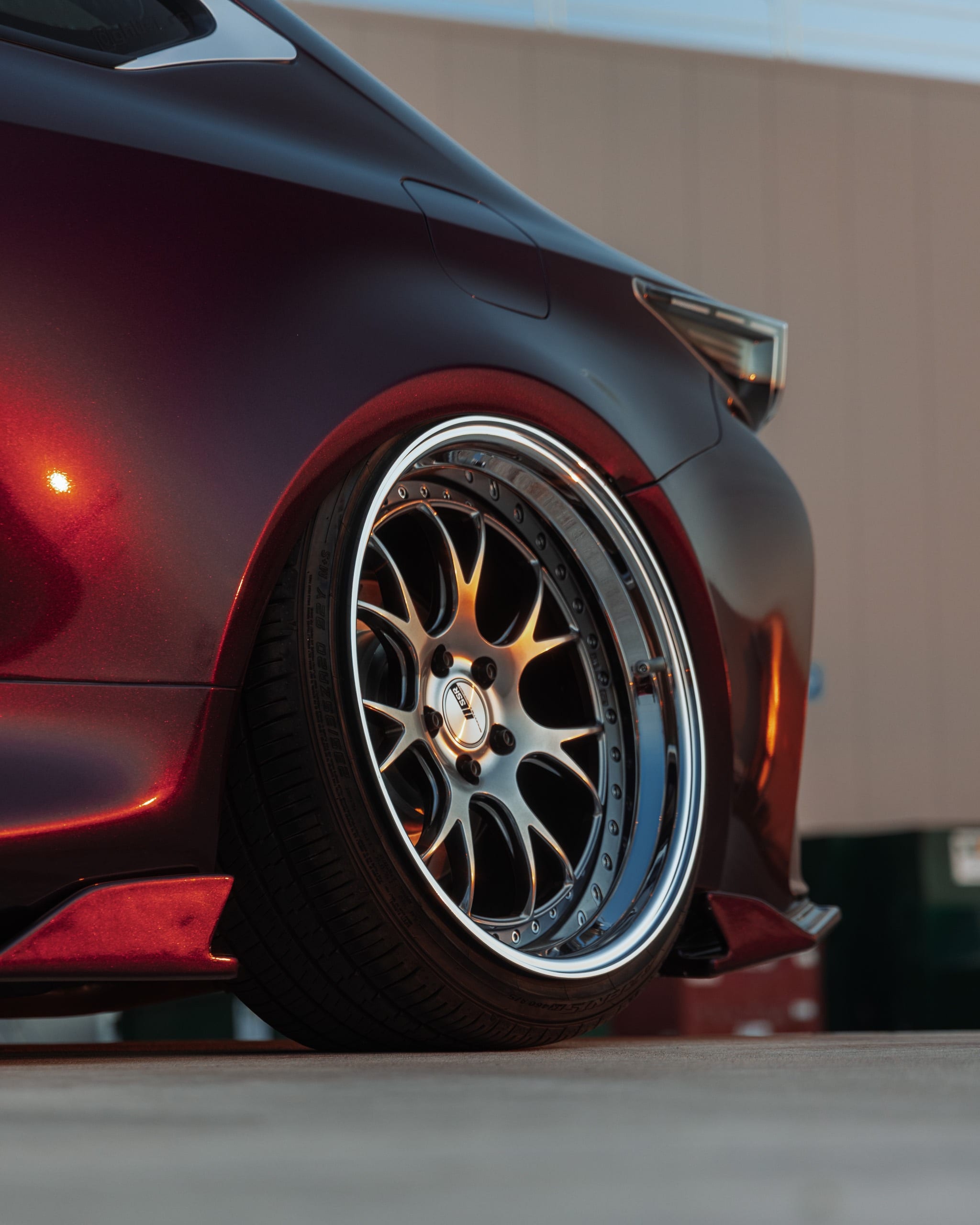 Low front-quarter detail of an air-suspended Lexus tucking its tire on a polished split-spoke wheel