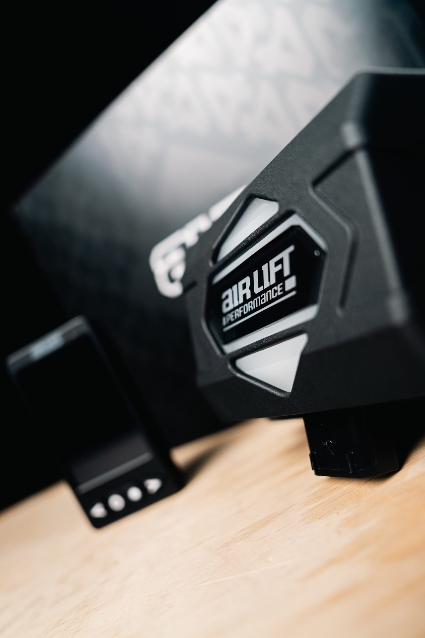 Studio close-up of the Air Lift Performance air management manifold and controller beside the retail box