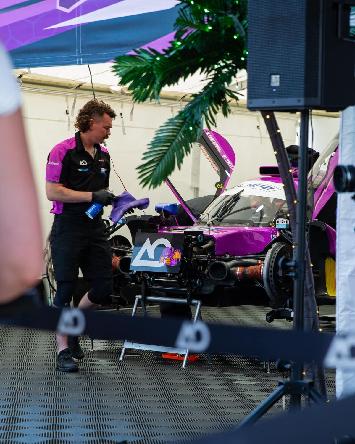 A crew member preparing a race car in the paddock before an event
