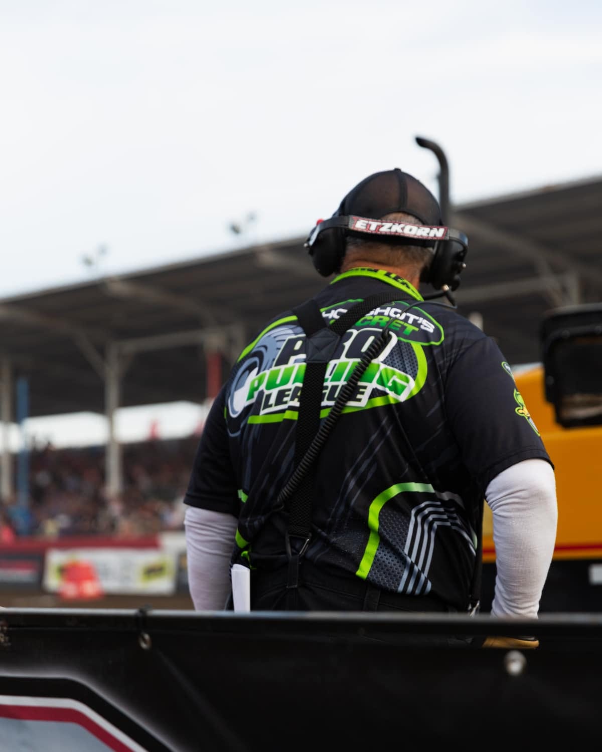 A crew member in team gear trackside at a diesel pulling event