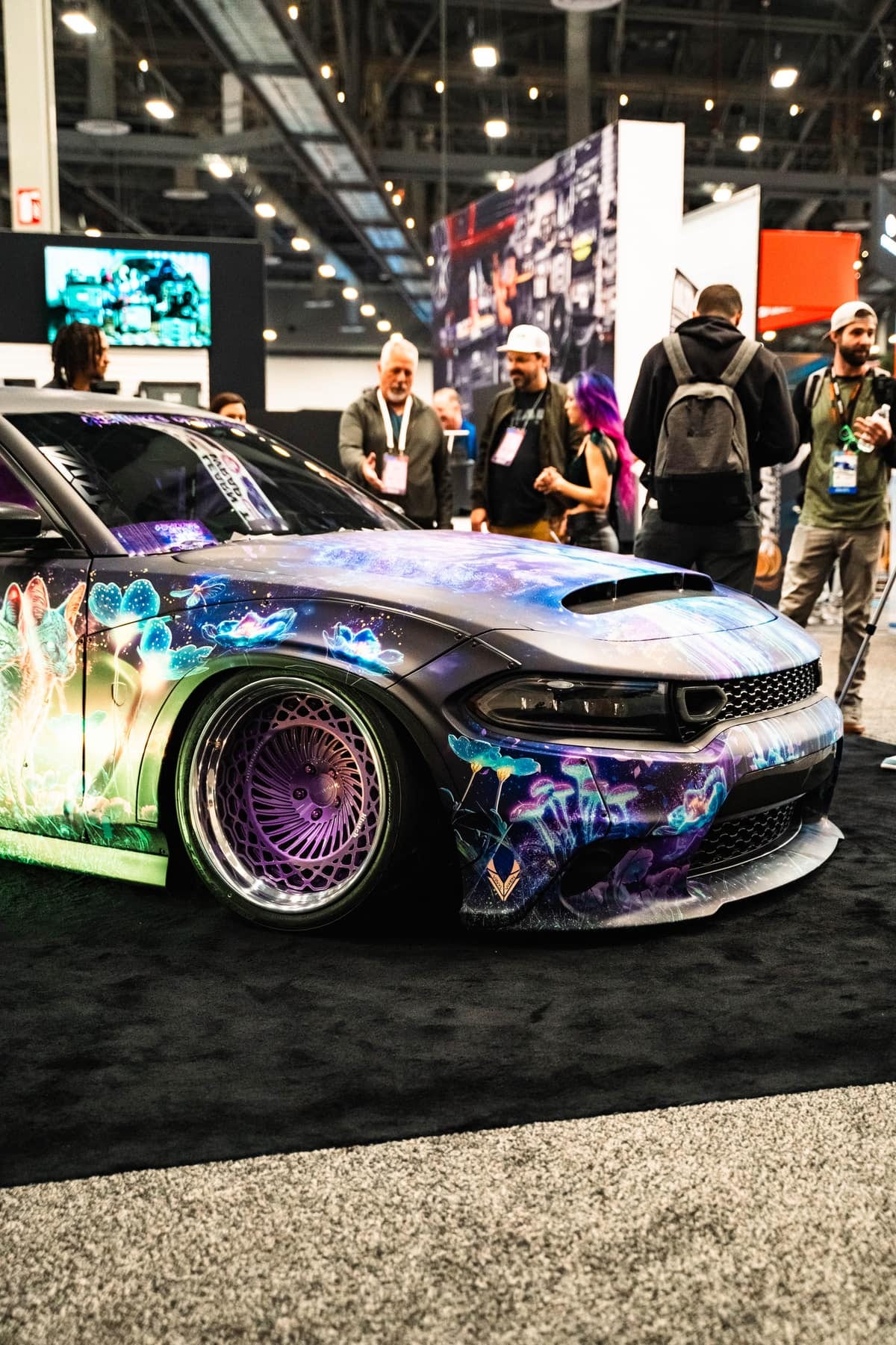 A custom galaxy-wrapped Dodge Charger on display at a SEMA show stand