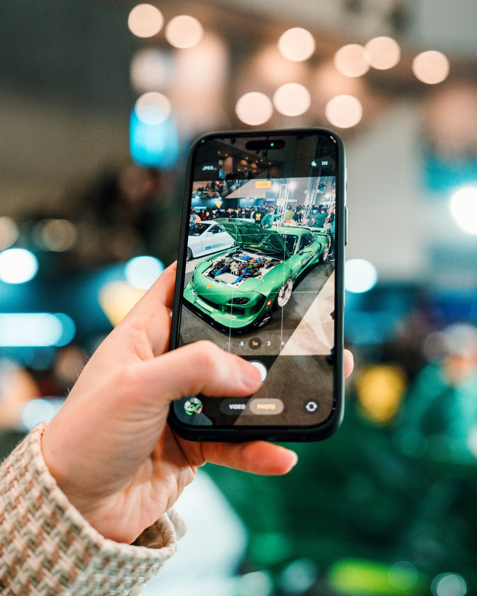 Attendee filming a tuner build on a phone at an enthusiast event